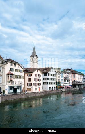 Zürich, Schweiz - 1. Juli 2024: Stadtbild am Flussufer - Altstadt von Zürich mit der berühmten Uhr der reformierten Kirche St. Peter Stockfoto