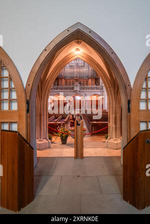 Zürich, Schweiz - 1. Juli 2024: Innenraum der reformierten Fraumunster-Kirche mit Holztüren, Bänken, Altar, Säulen und Orgel. Stockfoto