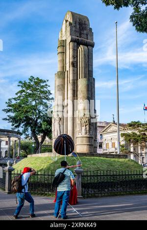 Ein Fotograf, der eine Frau vor einem Denkmal im Parque Centro América fotografiert. Quetzaltenango, Guatemala. Stockfoto