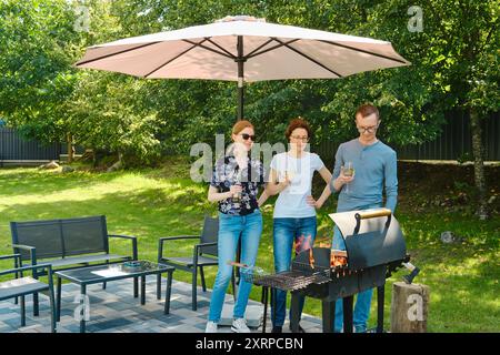 Die Familie versammelte sich neben einem Grill auf dem Rasen Stockfoto