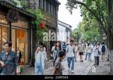 Suzhou, China - 11. Juni 2024 : Eine belebte Straße in Suzhou, China, mit Geschäften und Menschen, die vorbeilaufen. Stockfoto