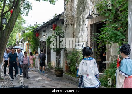 Suzhou, China - 11. Juni 2024 : Ein schmaler Steinweg in Suzhou, China, gesäumt von traditionellen Gebäuden und üppigem Grün. Stockfoto