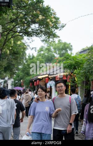 Suzhou, China - 11. Juni 2024 : Ein Paar spaziert Hand in Hand durch eine überfüllte Straße in Suzhou, China. Stockfoto