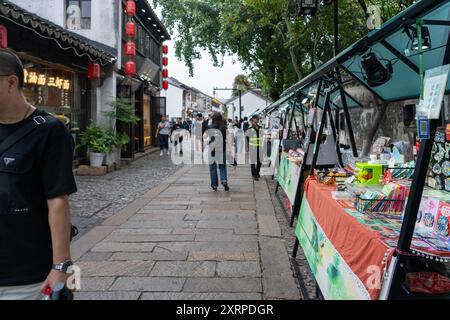 Suzhou, China - 11. Juni 2024 : Ein Straßenmarkt in Suzhou, China, wo Touristen an Verkaufsständen vorbeilaufen, die verschiedene Souvenirs verkaufen. Stockfoto