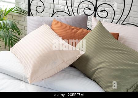 Gestreifte Kissen auf einem Bett mit Kopfteil aus schwarzem Metall Stockfoto
