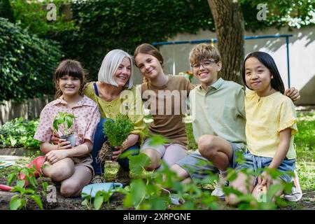 Porträt von Schülern und Lehrerinnen bei Outdoor Sustainable Education Class. Pflanzen von Gemüsesämlingen, Kräuter in den Boden. Das Konzept der Erlebniswelt Stockfoto