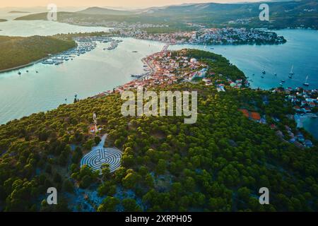 Panoramablick auf die Inseln in der Adria und das Heckenlabyrinth zwischen Waldbäumen bei Sonnenuntergang. Lavendellabyrinth in Rogoznica, Kroatien. Luftaufnahme von coasta Stockfoto