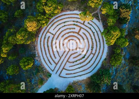 Aus der Vogelperspektive des kreisrunden Heckenlabyrinths umgeben von dichten Waldbäumen. Lavendellabyrinth in Rogoznica, Kroatien Stockfoto