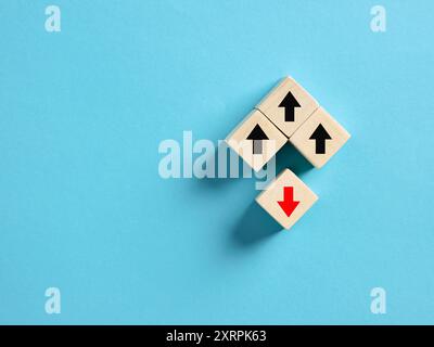 Holzblöcke auf blauem Hintergrund, drei mit schwarzen Pfeilen nach oben und einer mit rotem Pfeil nach unten. Abwärtsbewegung, Marktcrash, Misserfolg oder Erfolg Stockfoto