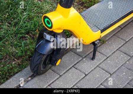 Ein leuchtend gelber Roller parkt ordentlich am Straßenrand und wartet darauf, dass der Besitzer zurückkehrt und sich im Sonnenlicht sonnt Stockfoto