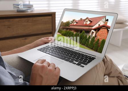Mann sucht Haus auf der Immobilienmarkt-Website zu Hause, Nahaufnahme Stockfoto
