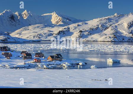 Malerische inuit-Siedlung in einem abgelegenen Fjord mit Eisbergen und Bergen, Winter, Sonne, Kulusuk, Ostgrönland, Grönland Stockfoto