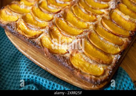 Ein Dessert aus geschnittenen Pfirsichen ist auf einem hölzernen Schneidebrett. Das Dessert ist mit Zucker bedeckt und sieht köstlich aus. Stockfoto