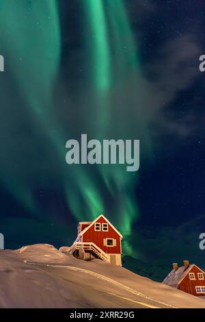 Grüne Nordlichter, aurora borealis über einem typischen grönländischen roten Haus, Tasiilaq, Ostgrönland, Grönland Stockfoto