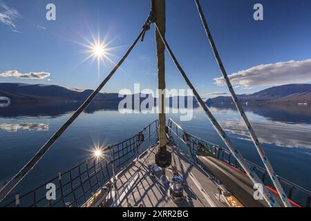 Segelboot in einem Fjord mit großen Eisbergen und Bergen bei Abendlicht, Scoresby Sund, Ostgrönland, Grönland Stockfoto