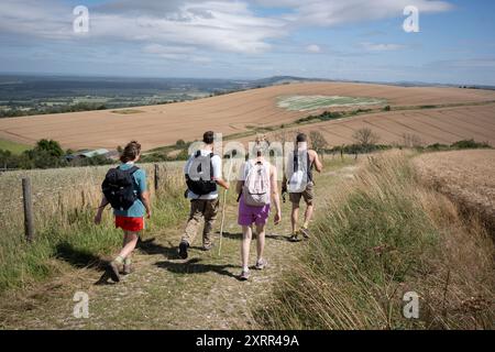 Eine Gruppe von Wanderern steigt am 10. August 2024 in Upwaltham, West Sussex, England vom Gipfel des Glatting Beacon auf dem South Downs Way in südöstlicher Richtung ab. Stockfoto