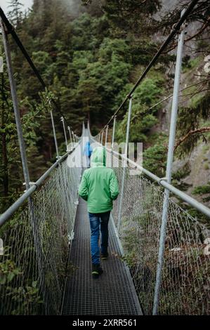 Zwei Jungs laufen auf einer Hängebrücke im regnerischen Wallis, Schweiz Stockfoto