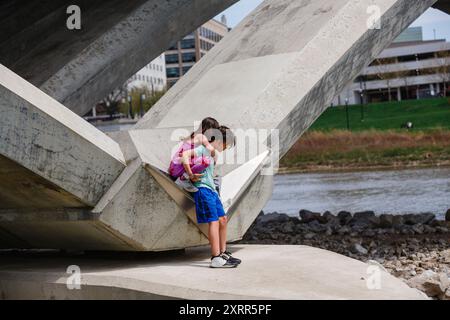 Der kleine Junge trägt ein kleines Mädchen vom Brückenstapel Stockfoto