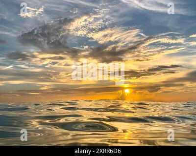 Nahaufnahme des Wassers im Ozean während des pulsierenden goldenen Sonnenuntergangs Stockfoto