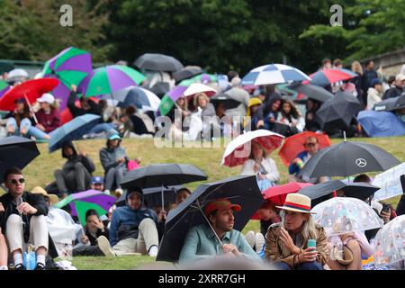 Zuschauer sitzen im Regen auf Henman Hill bei den Wimbledon Championships 2024 in London, England. Stockfoto