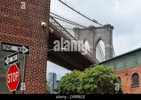 Allgemeine Sicht von unten auf die Brooklyn Bridge auf der Brooklyn-Seite des East River mit einem Stoppschild in New York City, New York, USA Stockfoto