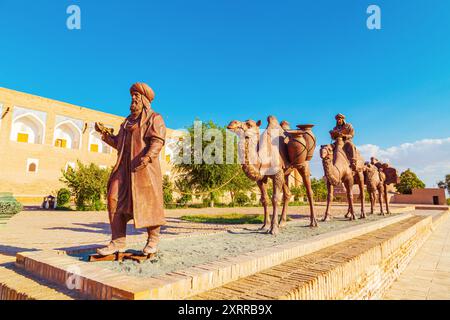 Skulpturengruppe einer Karawane mit Kamelen, die Güter entlang der Seidenstraße in der Nähe der alten Stadtmauern transportieren. Chiwa, Usbekistan - 16. Juli 2024. Stockfoto