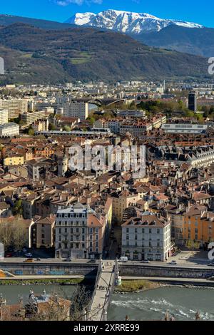 Stadtbild, Blick aus der Luft, hoch über den Dächern von Grenoble, Frankreich. Mit schneebedeckten Bergen in der Ferne. Schuss aus der Téléphérique-Seilbahn. Stockfoto