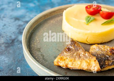 Meeresfischfilet gebraten und eine Beilage mit Kartoffelpüree in Nahaufnahme auf einem Teller auf dem Tisch. Restaurantservice. Platz für Text. Kindermenü Stockfoto