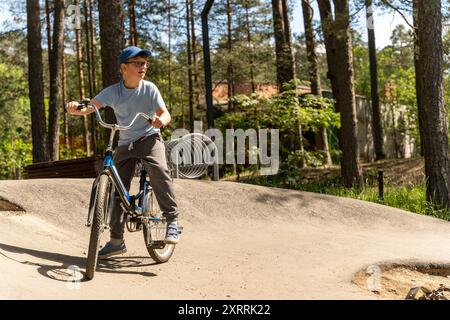 Ein kleiner Junge fährt an einem sonnigen Tag auf einem Weg durch einen Wald mit dem Fahrrad Stockfoto