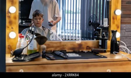 Ein kleiner Junge sitzt in einem Friseurstuhl und bekommt einen Haarschnitt Stockfoto