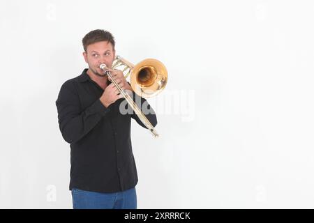 Schöner junger Mann mit Posaune auf weißem Hintergrund Stockfoto