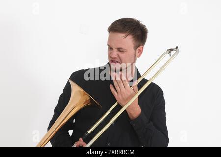 Schöner junger Mann mit Posaune auf weißem Hintergrund Stockfoto