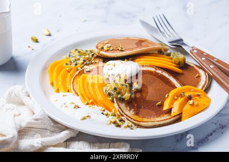 Frühstückspflanzkuchen mit Mango und Passionsfrucht auf einem weißen Teller. Gesundes veganes Rezept. Stockfoto