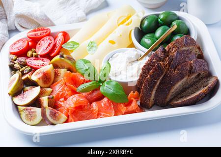 Lachs, Käse, Oliven, Brot und Gemüse Frühstücksteller, weißer Hintergrund. Stockfoto