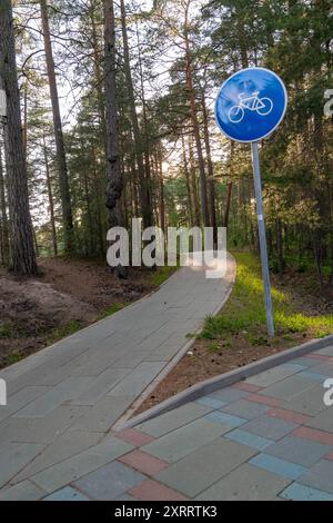 Der Pfad schlängelt sich durch Kiefernwälder mit blauem Fahrradschild. Stockfoto