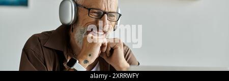 Ein reifer schwuler Mann mit Tattoos und grauen Haaren lächelt, während er von zu Hause aus arbeitet. Stockfoto