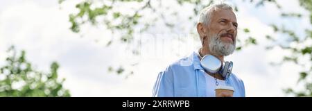 Ein reifer Schwuler mit Tattoos und grauem Bart, der die frische Luft genießt. Stockfoto