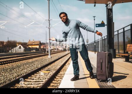 Ein wütender Mann mit einem Koffer, der auf einem Bahnhof steht. Stockfoto