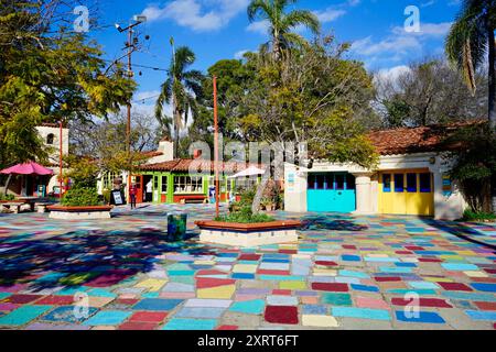 Ein lebhafter, farbenfroher plaza mit bunten Fliesen, lebhaften Gebäuden und tropischem Grün unter einem hellblauen Himmel. Stockfoto