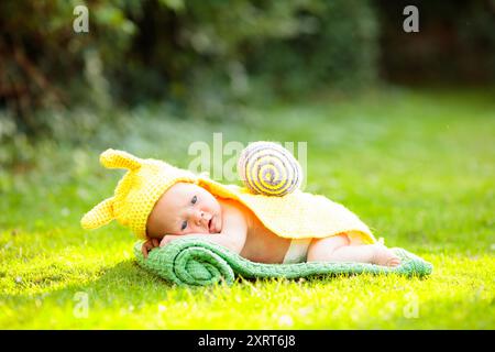 Baby in süßem Kostüm. Neugeborenes im Garten. Niedliches Nickerchen im Sommerpark. Stockfoto