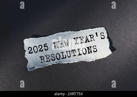 Neujahrsvorsätze 2025 - Text über zerrissenes Papier auf dunklem Schreibtisch im Sonnenlicht Stockfoto