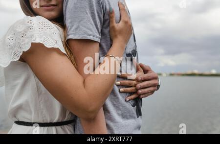 Seitenansicht eines ruhigen, entspannten Paares, das die Landschaft vom Pier aus genießt und eine Frau einen Mann umarmt Stockfoto