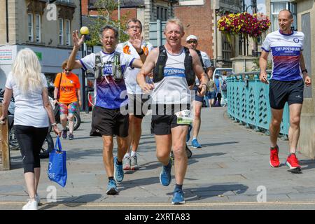 Chippenham, Wiltshire, Großbritannien. August 2024. Der 54-jährige Ultramarathonläufer Frank Wainwright (Mitte) läuft am 43. Tag seiner Englandreise durch seine Heimatstadt Chippenham. Er hat sich die Herausforderung gestellt, 62 Ultramarathons in 62 Tagen zu laufen, um Mittel für eine Reihe von Wohltätigkeitsorganisationen zu sammeln, darunter den Brathay Trust, der junge Menschen zu positiven Veränderungen inspirieren soll. Er machte sich am 1. Juli in Newcastle auf und wird seine Tour Ende August in Newcastle beenden. Quelle: Lynchpics/Alamy Live News Stockfoto