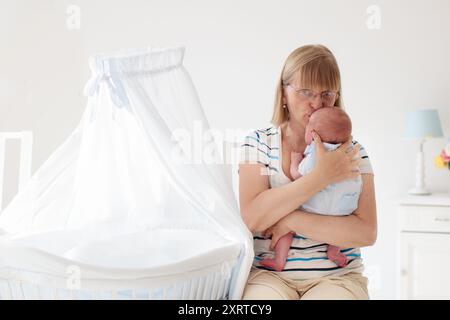 Mutter und Kind auf einem weißen Bett. Mama und Baby in Windel spielen im sonnigen Schlafzimmer. Eltern und kleine Kinder entspannen sich zu Hause. Familie, die Spaß hat Stockfoto