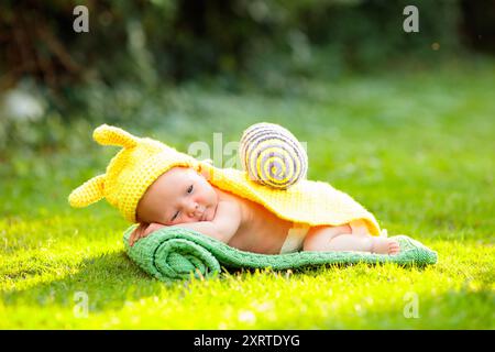 Baby in süßem Kostüm. Neugeborenes im Garten. Niedliches Nickerchen im Sommerpark. Stockfoto