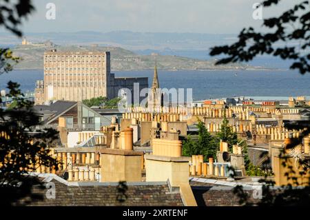 Edinburgh Dächer mit Kaminen und malerischer Küste im Hintergrund Stockfoto