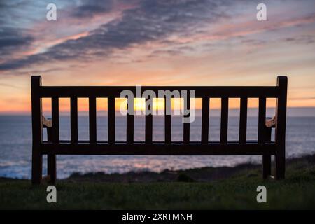 Alte Holzbank mit Blick auf das Meer bei Sonnenuntergang. Stockfoto