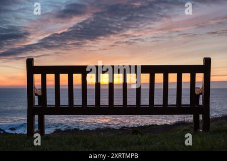 Alte Holzbank mit Blick auf das Meer bei Sonnenuntergang. Stockfoto