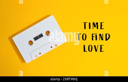 Ein weißes Kassettenband ist auf gelbem Hintergrund mit den Worten Time to Find Love drunter Stockfoto