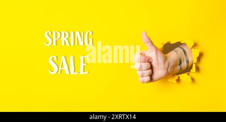 Eine Hand, die einen Daumen nach oben gibt, mit den Worten Spring Sale darunter. Das Bild hat eine helle und positive Stimmung, die ein Gefühl der Begeisterung und vermittelt Stockfoto